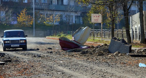 Люди едут на автомобиле рядом с поврежденным зданием после обстрела в городе Шуши (Шуша), 29 октября 2020 года. Фото:  Ваграм Багдасарян/Photolure via REUTERS 