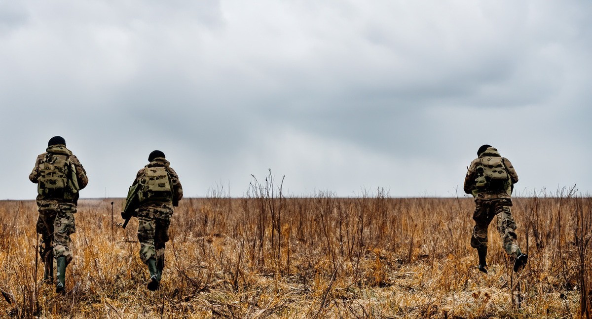 Военные идут по полю. Иллюстрация создана «Кавказским узлом» с помощью ИИ в программе Photoshop